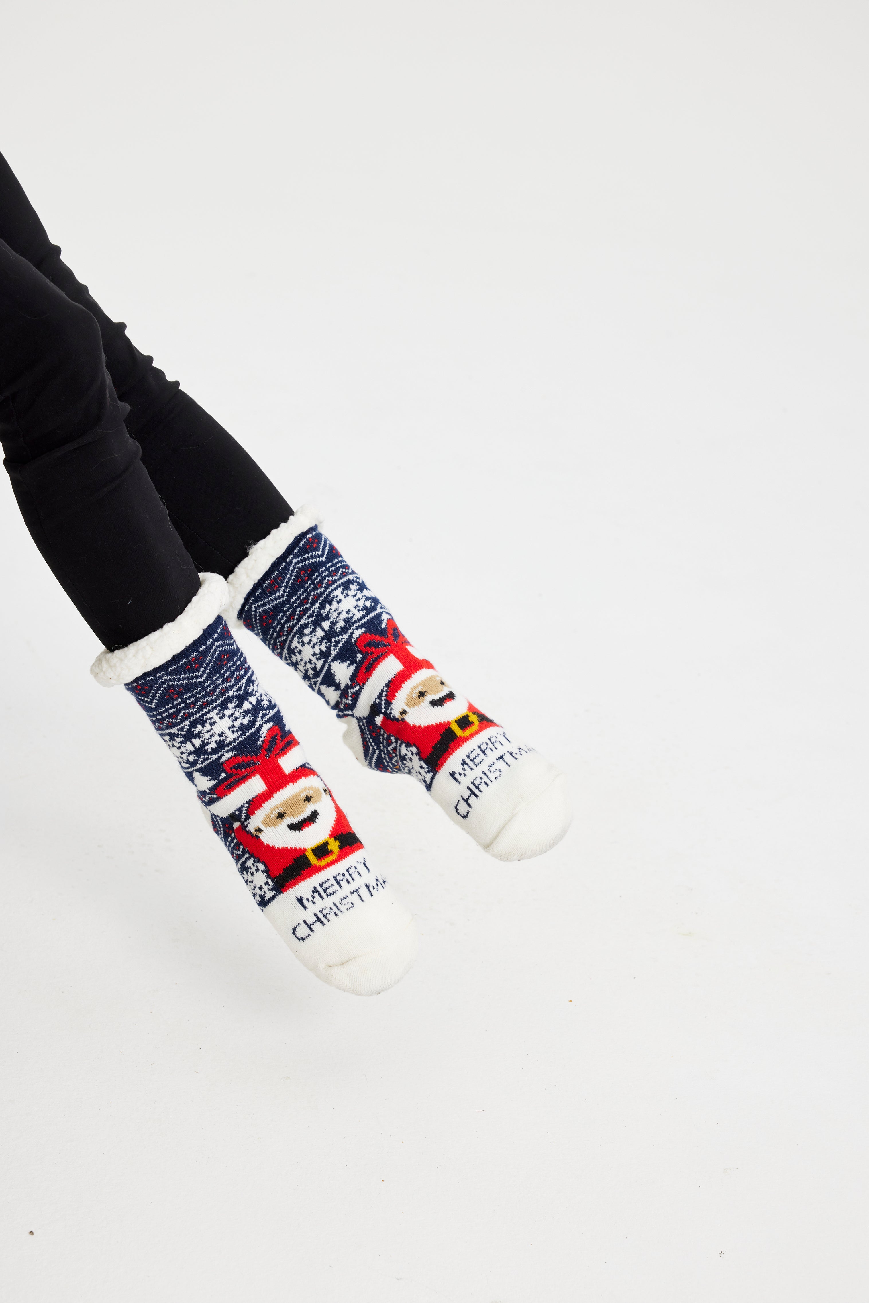 Ett par fötter i blå julstrumpor med jultomten och snöflingor på.